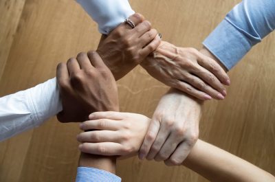 Diverse business people team grasping hands, close up top view Diverse business people team grasping hands, close up top view