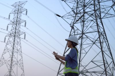 Female electrical engineer working near to High voltage tower. Female electrical engineer working near to High voltage tower.