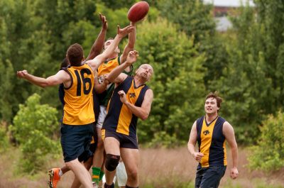 Players Jump To Catch Ball In Australian Rules Football Game Players Jump To Catch Ball In Australian Rules Football Game