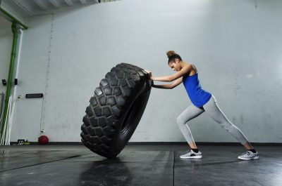 Young girl flipping tire at the gym