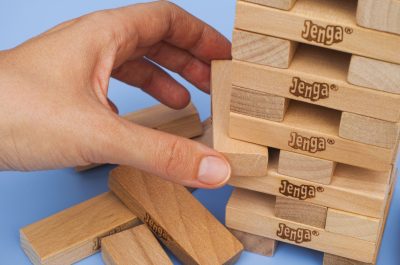 Human hand removing one block from Jenga tower