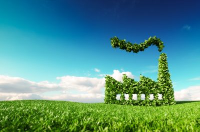Eco friendly industry concept. 3d rendering of green factory icon on fresh spring meadow with blue sky in background. Eco friendly industry concept. 3d rendering of green factory icon on fresh spring meadow with blue sky in background.