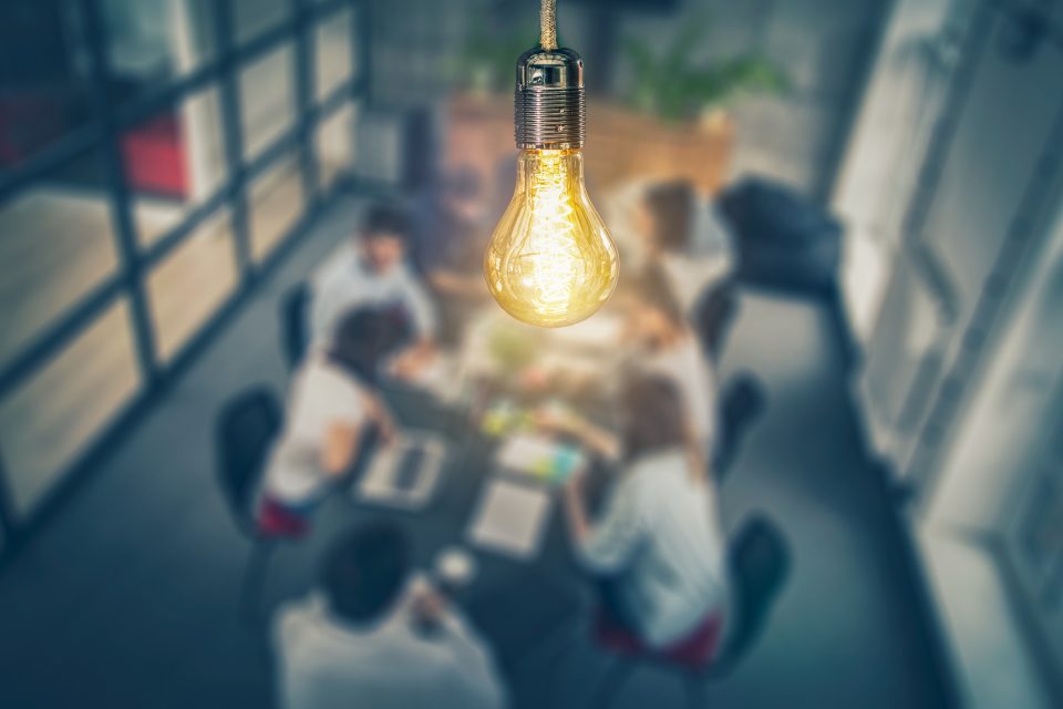Young creative business people meeting at office. Young business people are discussing together a new startup project. A glowing light bulb as a new idea.