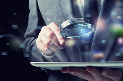 Businessman examines a tablet with a magnifying glass. Concept of internet security Businessman examines a tablet with a magnifying glass. Concept of internet security